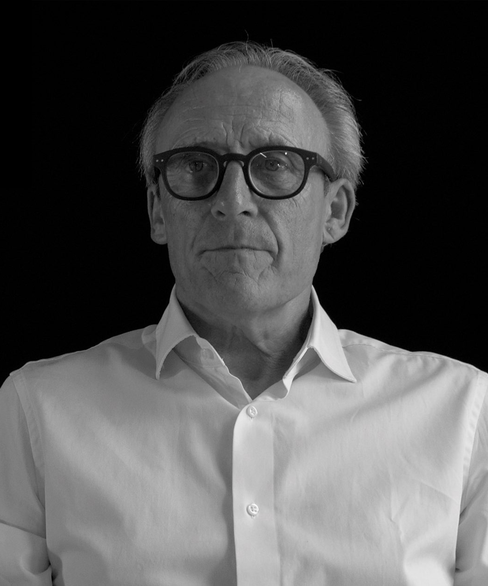 black and white headshot of man wearing white shirt and glasses