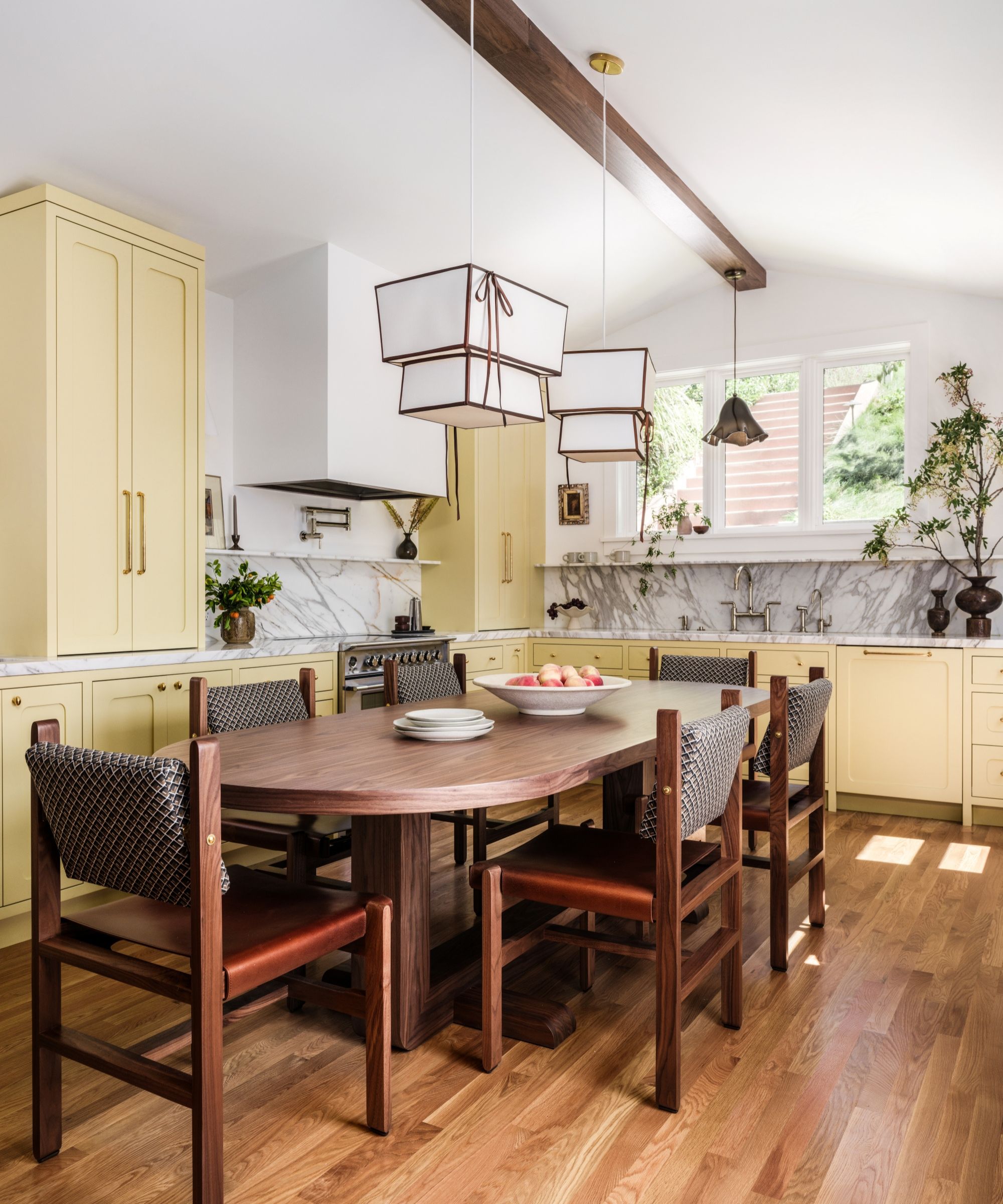 a yellow kitchen with marble countertops and a large wooden table at the center