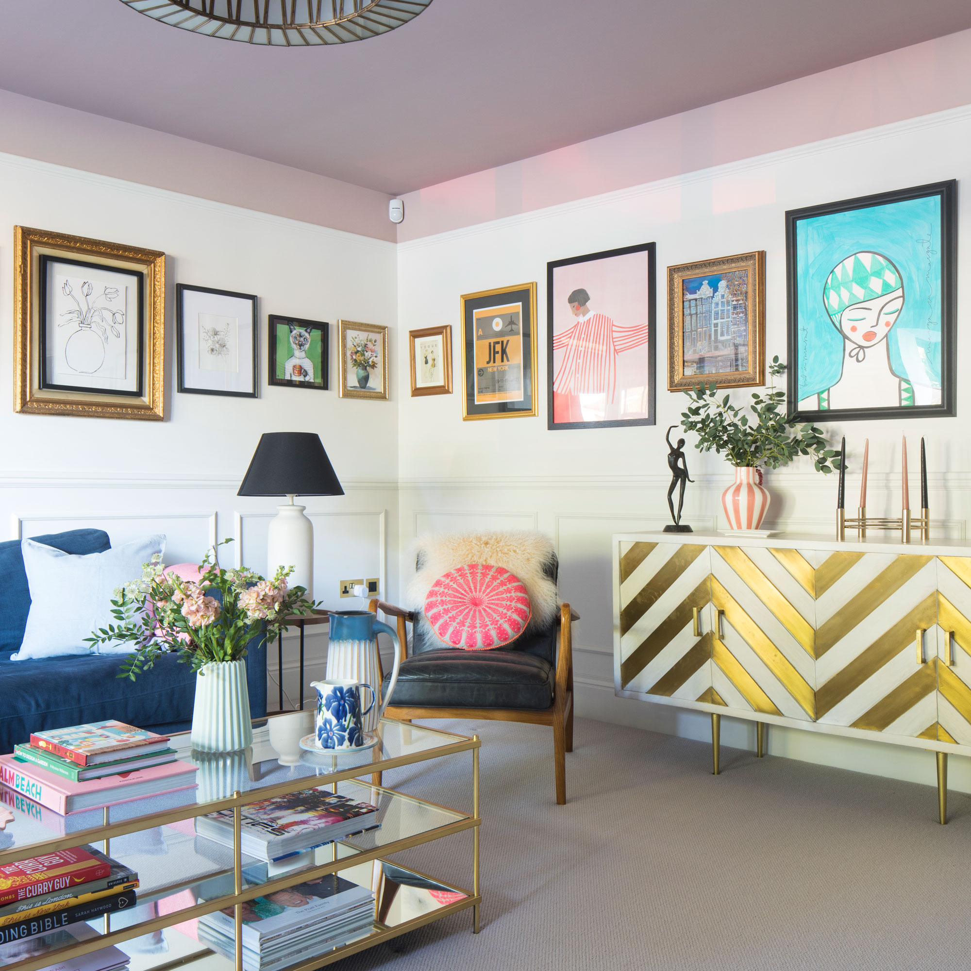 Living room with gallery wall, armchairs, gold chevron sideboard and glass coffee table