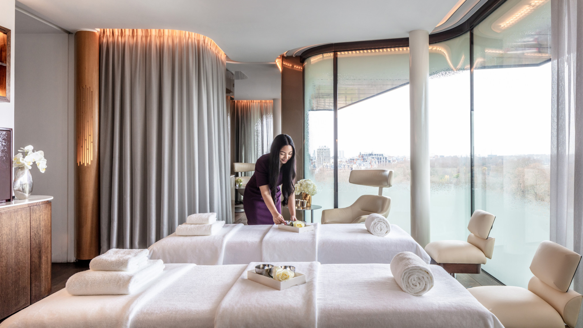 A wide shot of a treatment room in the spa with glass windows overlooking Hyde Park