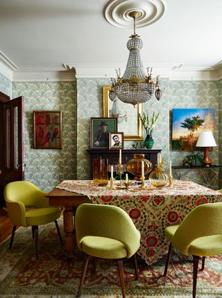 dining room with floral tablecloth and yellow chairs in room with artwork vintage rug and leopard wallpaper