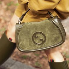 a guest at Milan Fashion Week walks down the street with a suede Gucci blondie bag