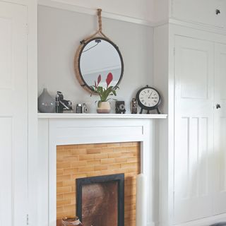 A fireplace with alcoves on either side filled with fitted wardrobes in white