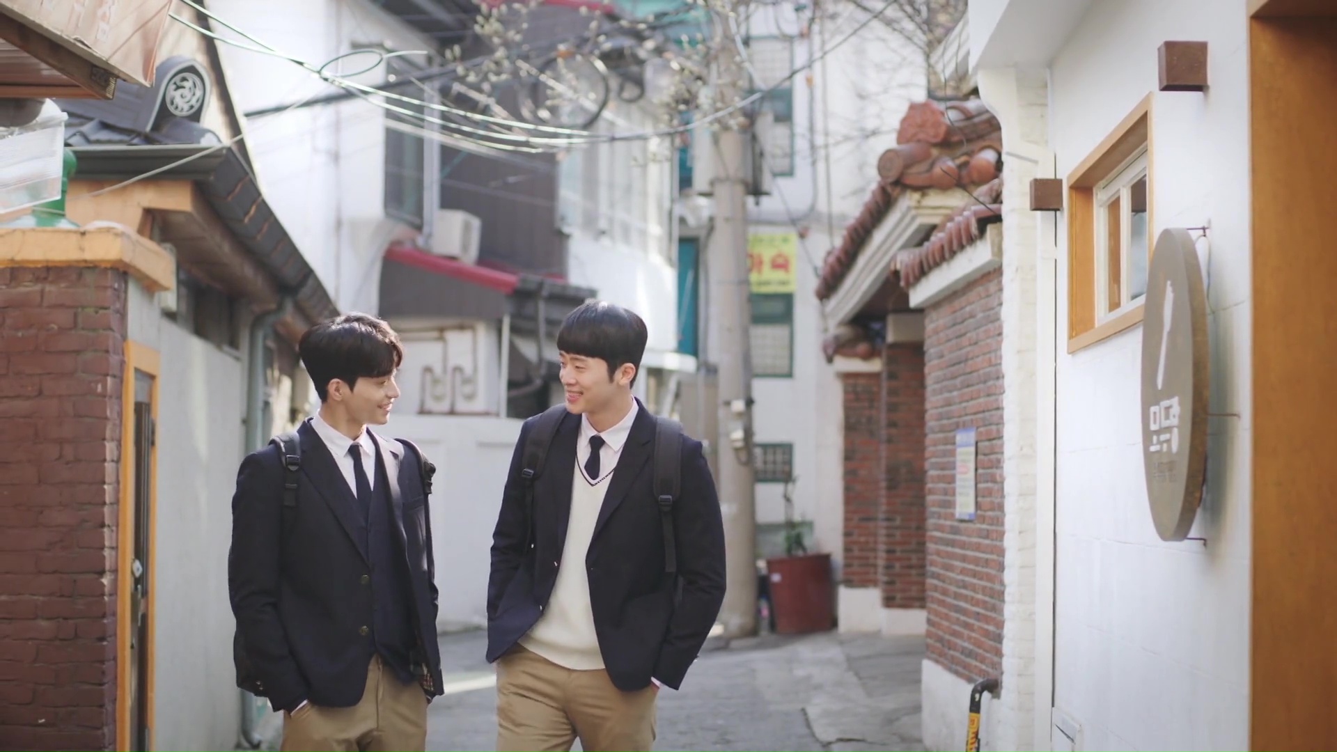 Two boys in high school uniforms walk down a Korea alleyway, in 'Where Your Eyes Linger.'