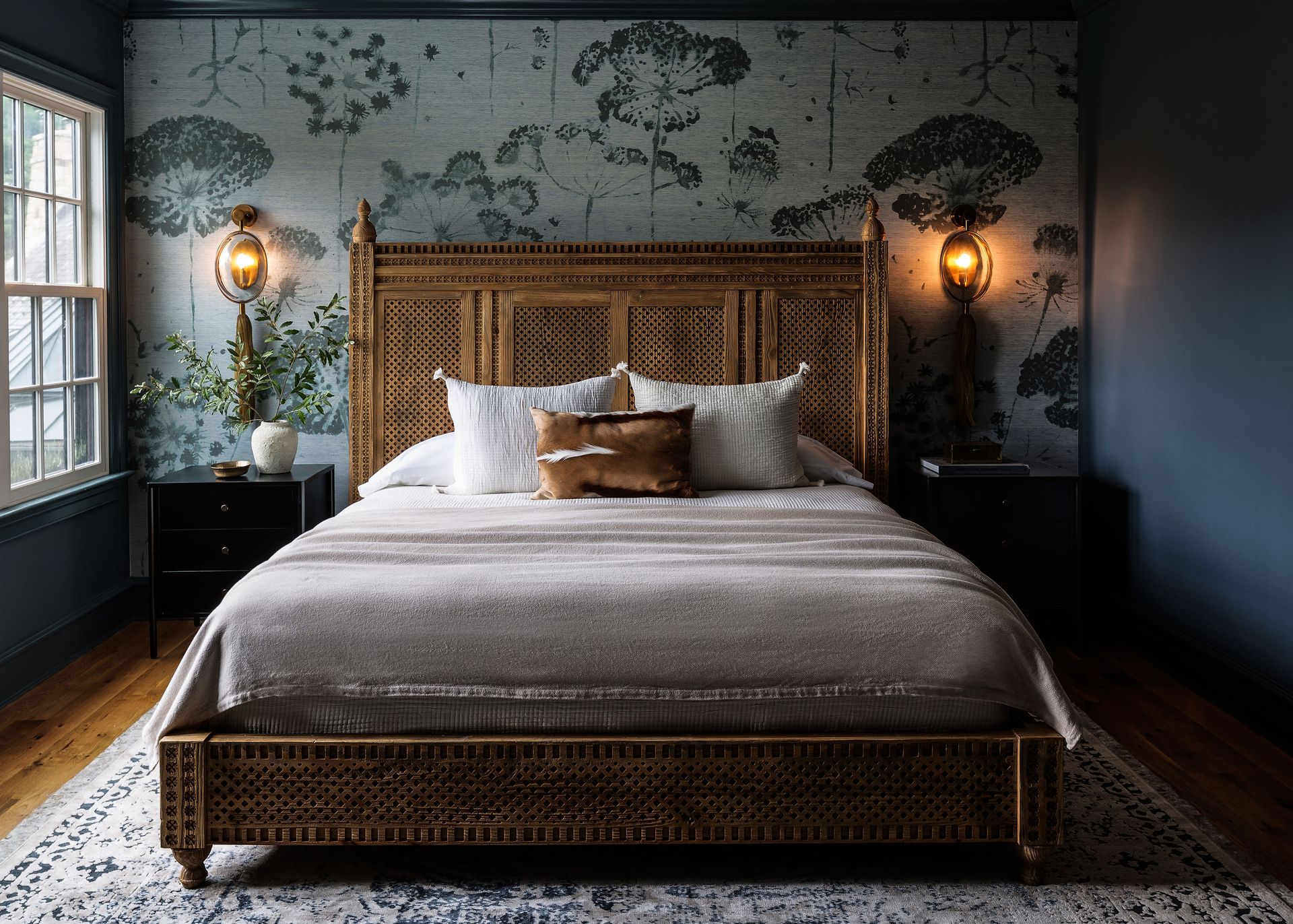 A bedroom with blue walls and a botanical wallpaper accent wall