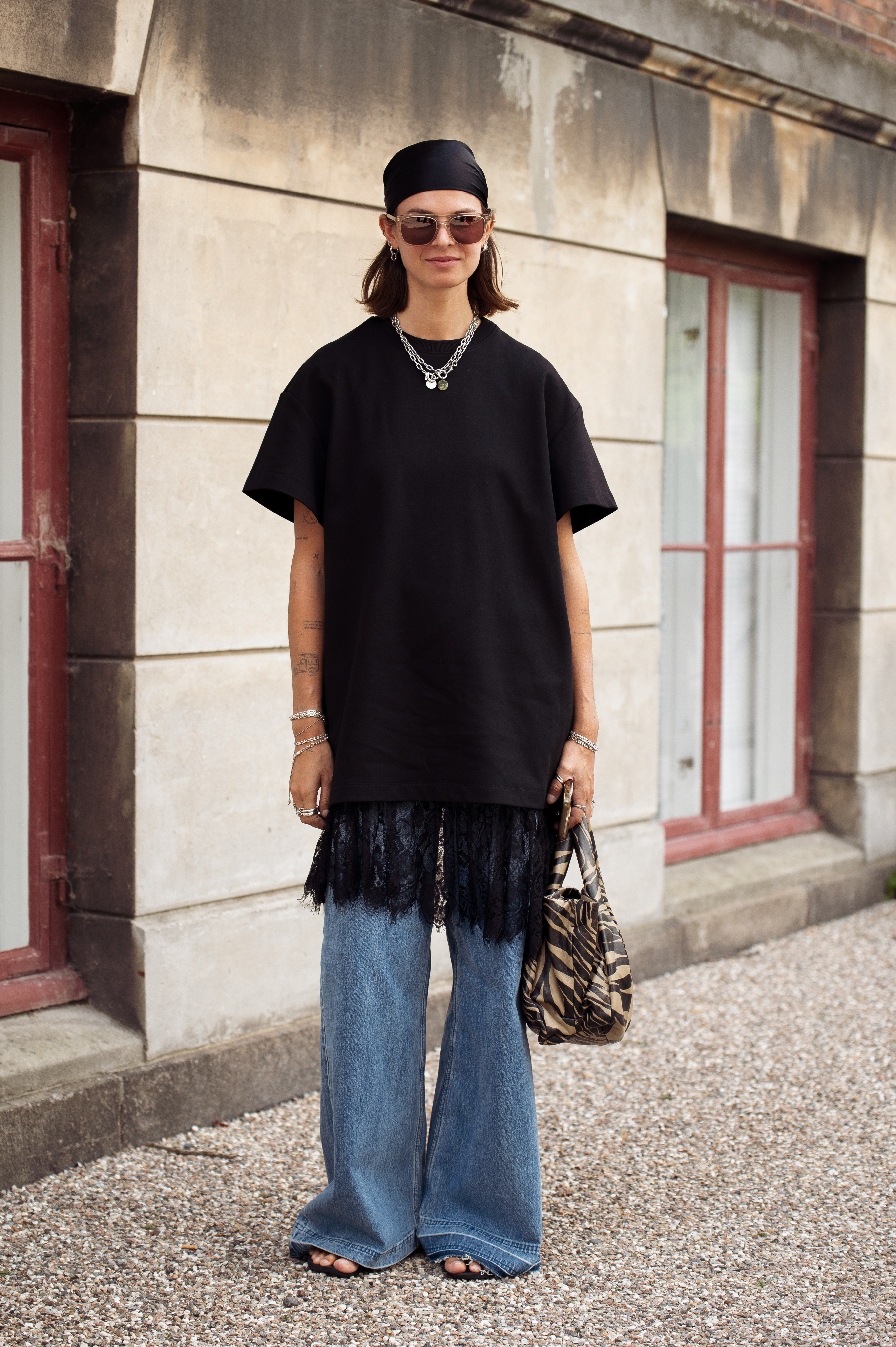 Photo of Scandi woman wearing black t-shirt and lace slip skirt over jeans during Copenhagen Fashion Week.