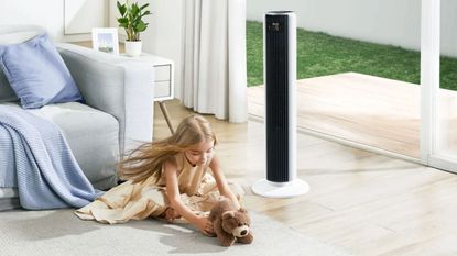 A Levoit 36 Inch Tower Fan in a modern living room next to a child playing with a teddy bear