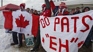 New England Patriots fans waving a Canada flag before an NFL game.
