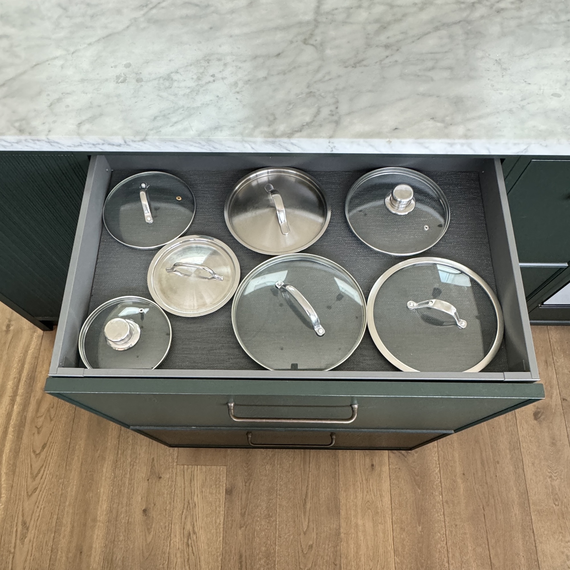 pans in green hidden kitchen drawer with wooden flooring