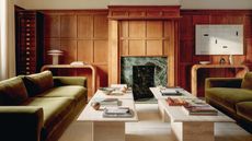 Living room with oak paneling, green velvet sofas and travertine coffee tables