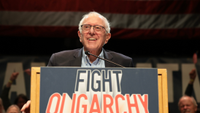 Bernie Sanders on a podium with a Fight Oligarchy sign