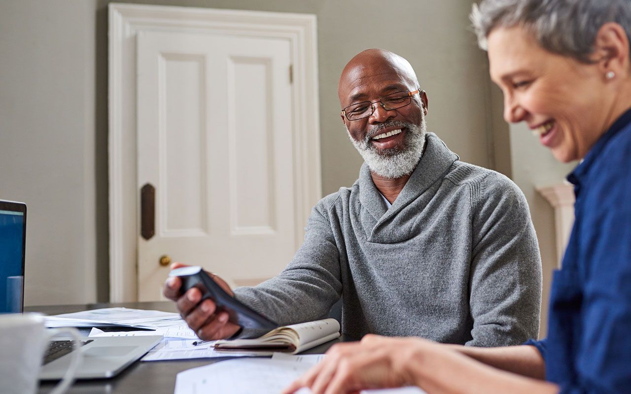 A senior couple smile as they go over their expenses