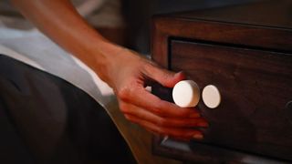 Woman detaching Philips Hue Smart Button from base stuck on nightstand