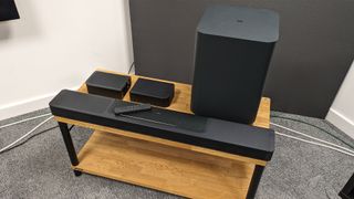 JBL Bar 1300 soundbar system on wooden TV stand with remote