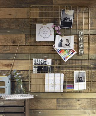 steel wire mesh noticeboard with pictures on wooden wall