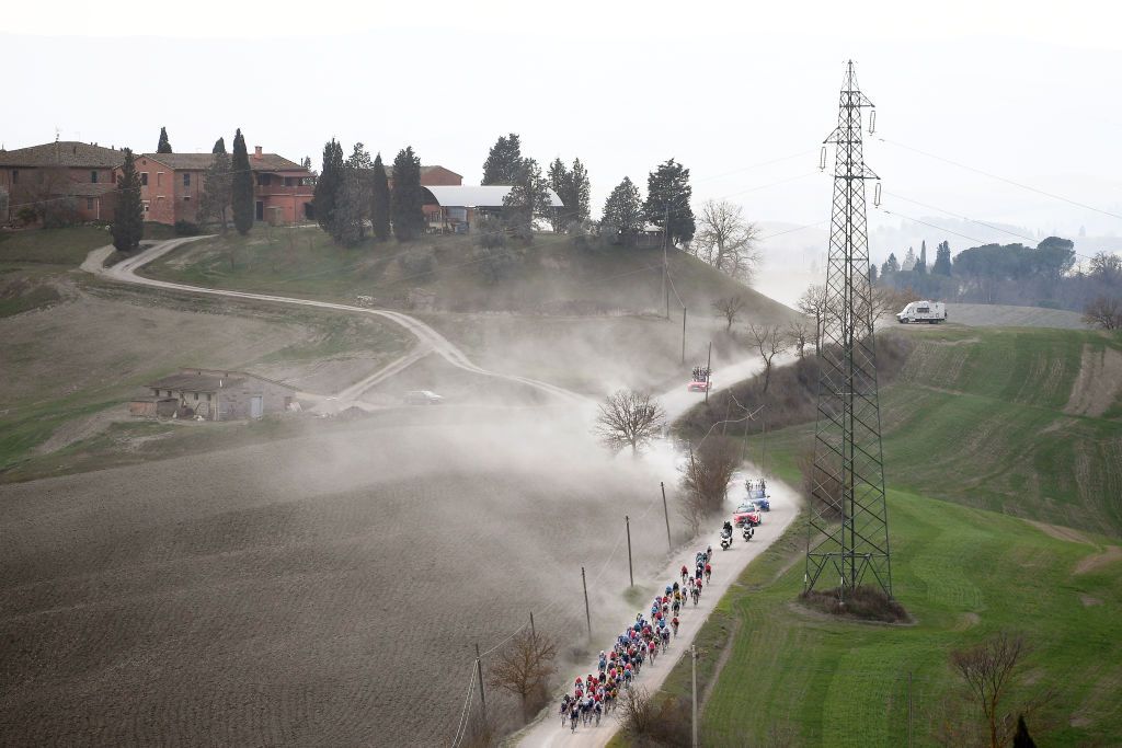 SIENA ITALY MARCH 05 The peloton passing through a dusty gravel strokes sector during the Eroica 16th Strade Bianche 2022 Mens Elite a 184km one day race from Siena to Siena Piazza del Campo 321m StradeBianche WorldTour on March 05 2022 in Siena Italy Photo by Tim de WaeleGetty Images