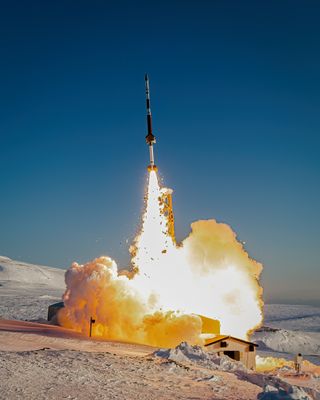 a small rocket lifts off above a snowy landscape