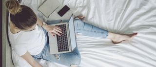 Coursera review 2021: Image shows young woman on bed studying with laptop and notepad