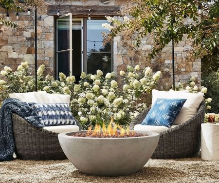 Basket-style chairs with a firepit in a rustic country garden of a stone house