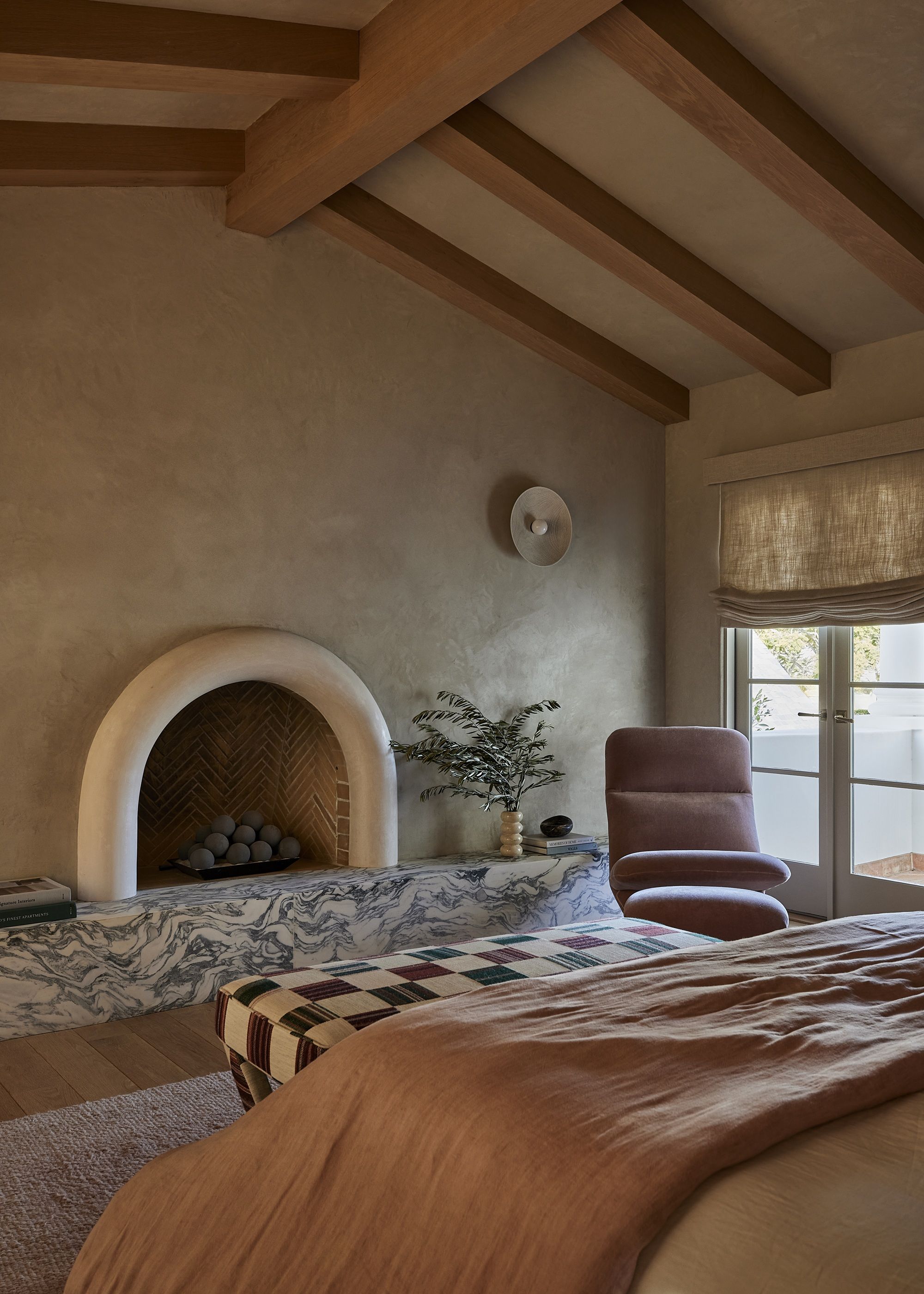 a bedroom with timber beams, a marble fireplace and arched bedroom fireplace