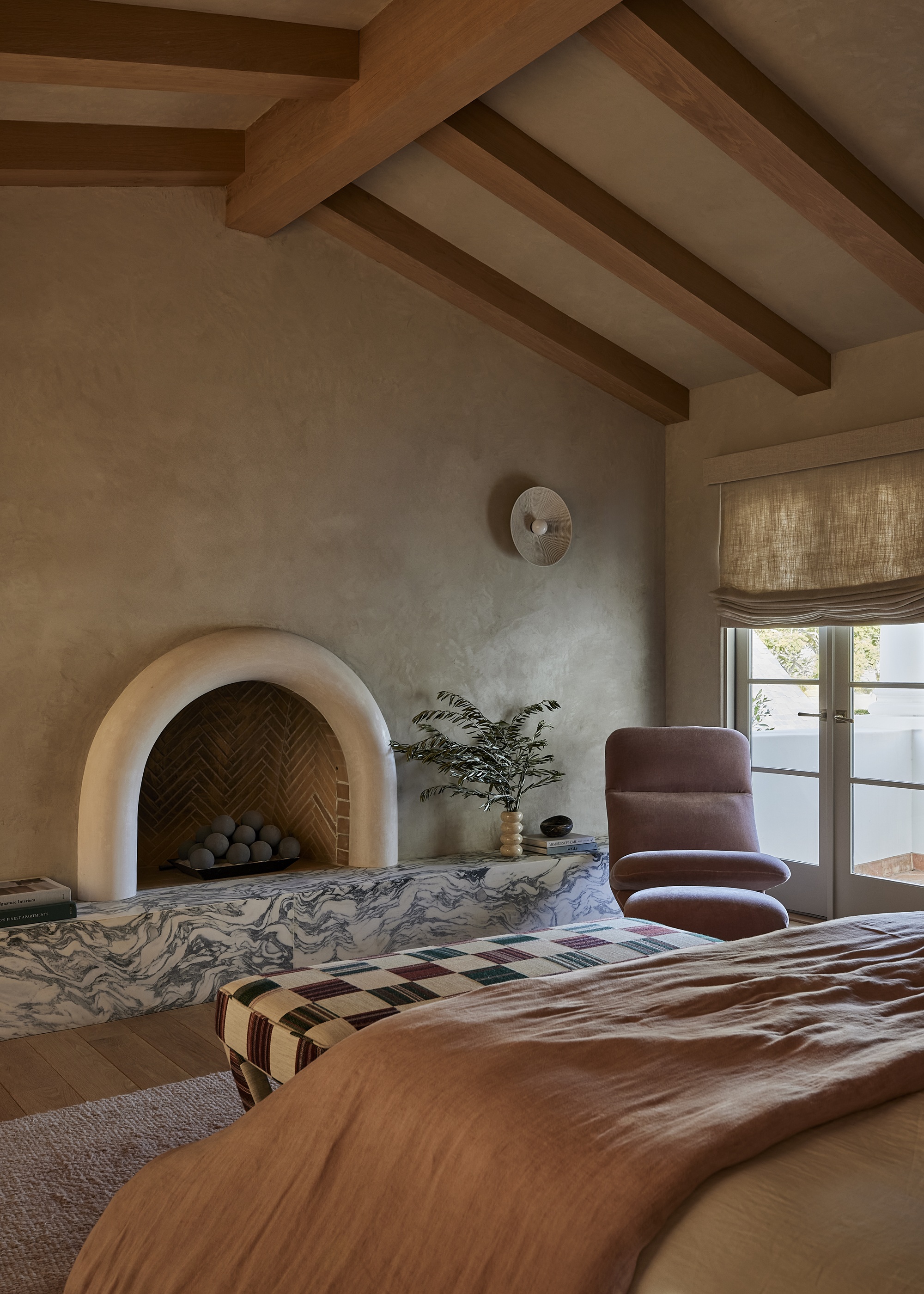 a bedroom with timber beams, a marble fireplace and arched bedroom fireplace