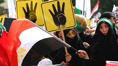 Protesters hold placards showing the 'Rabia sign' which has become the symbol of the Rabaa massacre