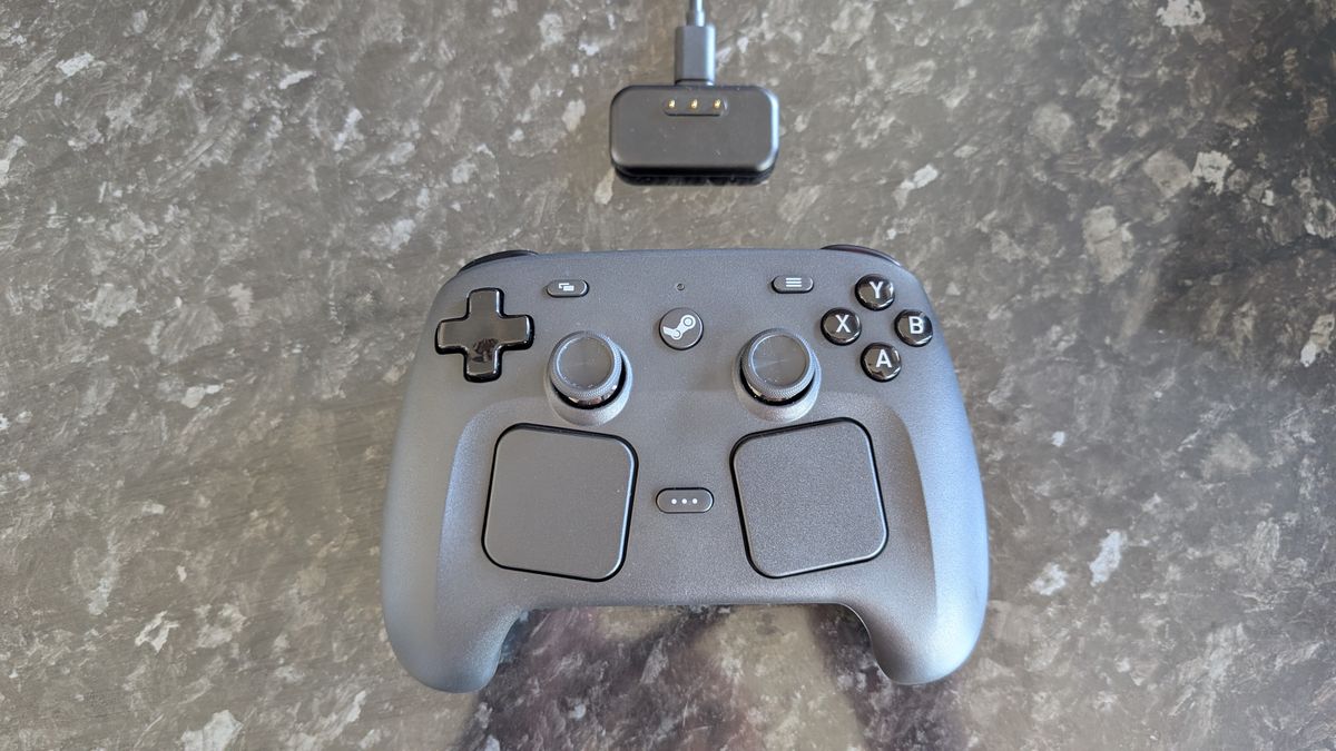 The Valve Steam Controller with charging puck, pictured on a dark marble worktop.