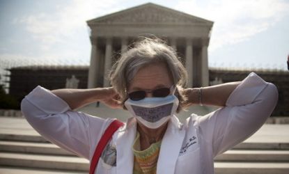 A pro-ObamaCare demonstrator stands outside the Supreme Court on Monday: Only 10 percent of Americans believe the Supreme Court will uphold the health care law in full.