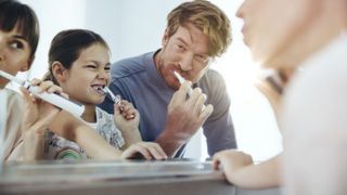 Can you use an electric toothbrush with braces: image shows family brushing teeth