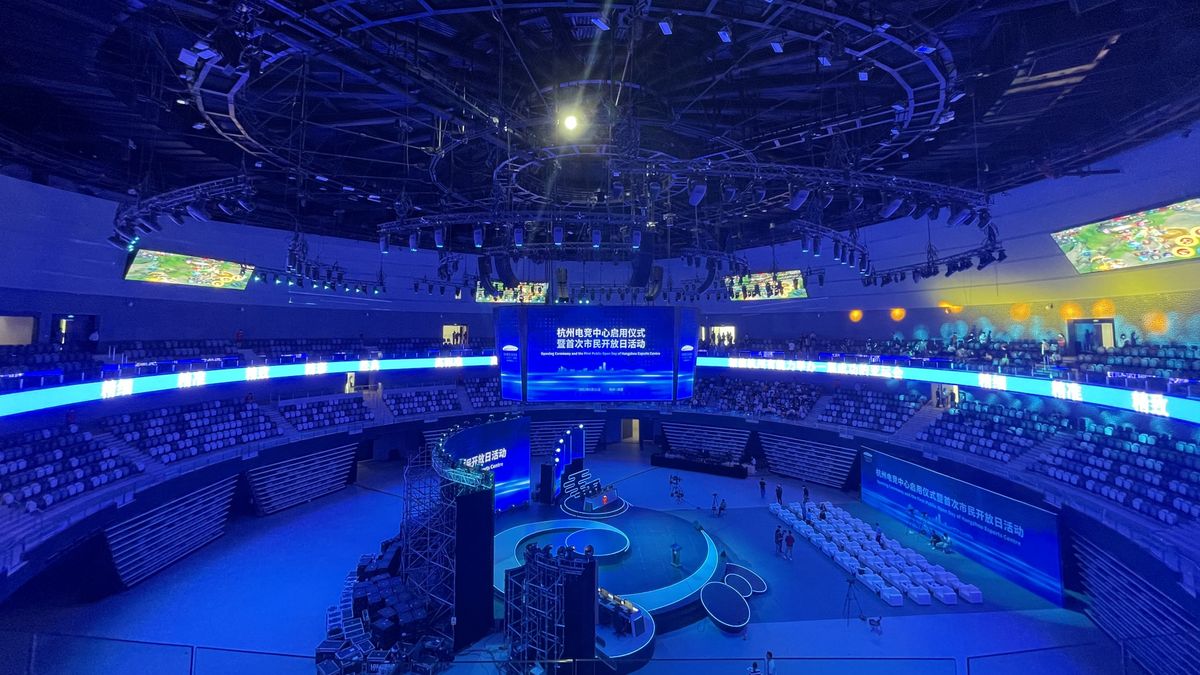 An empty esports arena dimly lit with a digital centerhang display.