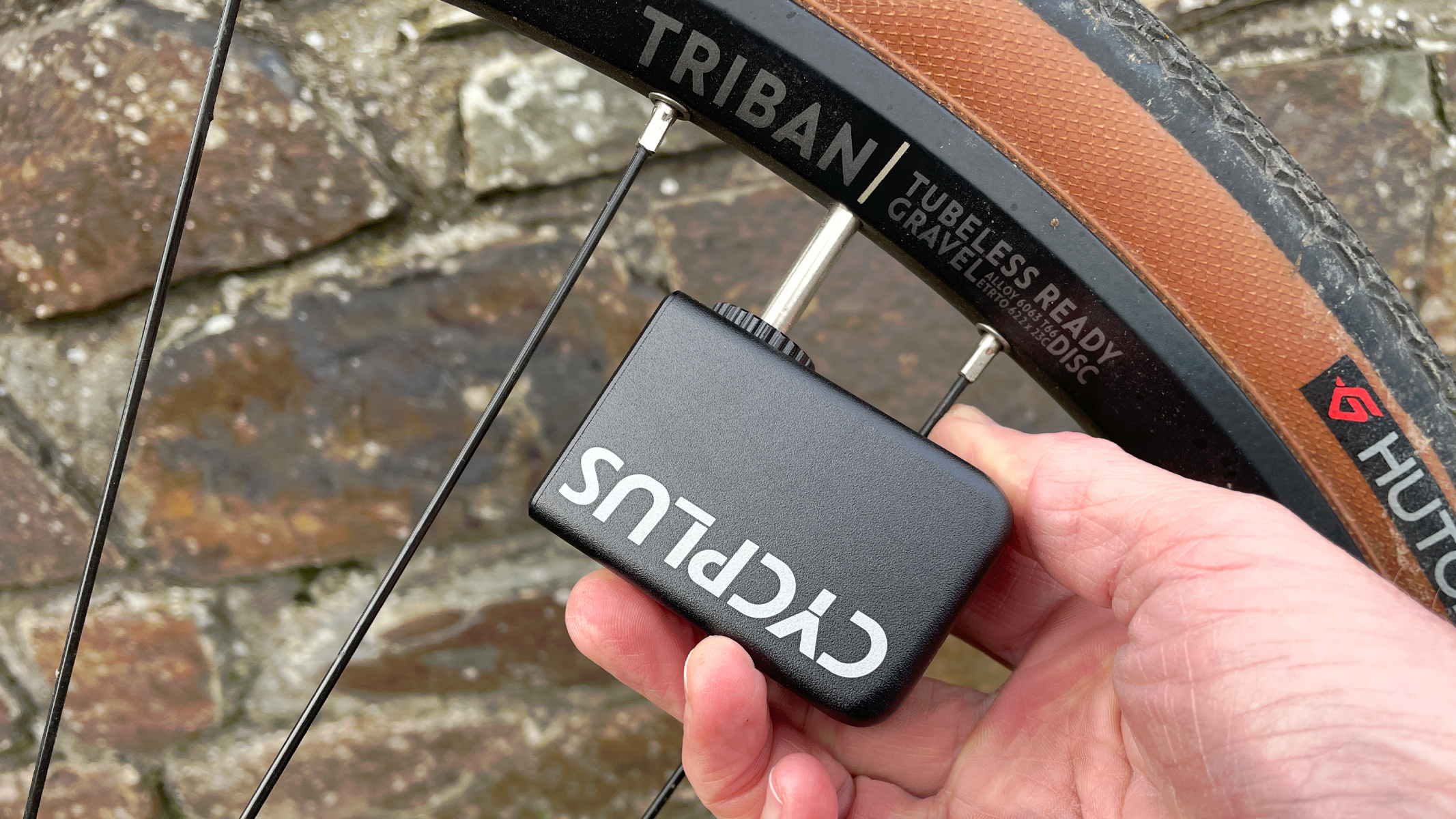 The Cycplus AS2 portable electric bike pump being used on a gravel bike wheel