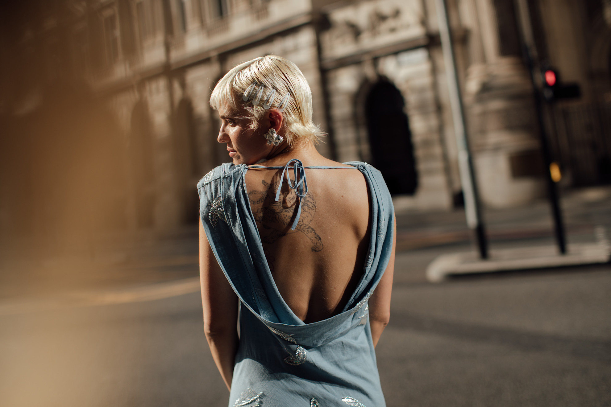 women with blonde pixie haircut and barrettes in blue low back dress