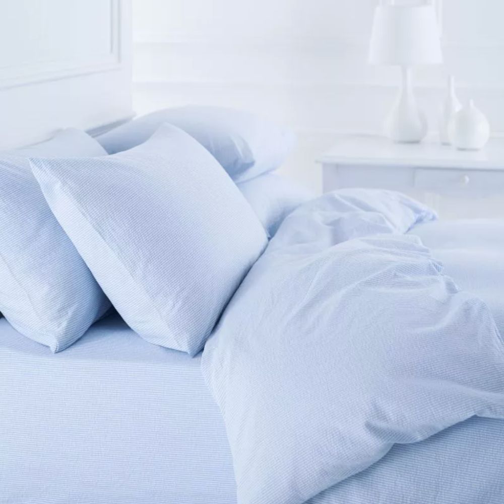 Pale blue seersucker cotton bedlinen made up on a bed