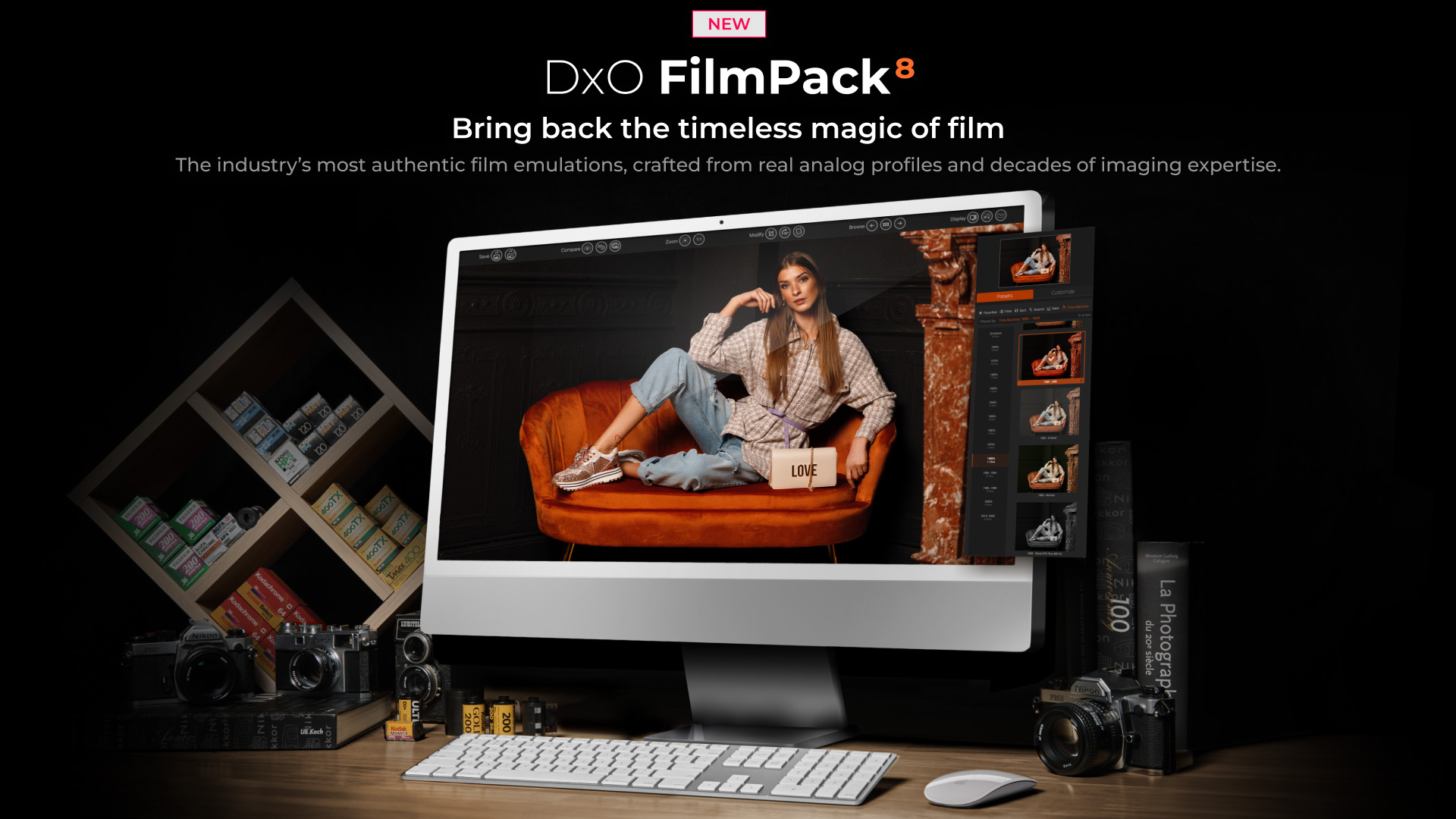 Promotional image of computer running DxO FilmPack 8 in a dark room on top of a desk surrounded by film cameras and boxed film 
