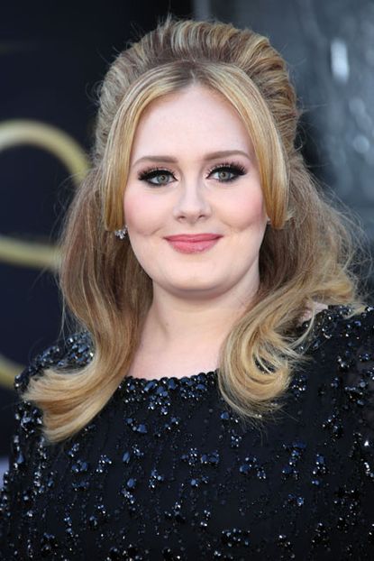 Adele with her hair worn loose and a sAdele in a black sequin dress with high volume hairtatement red lip on Oscars night