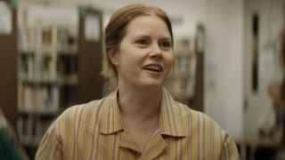 Amy Adams smiling among friends in a library in Nightbitch