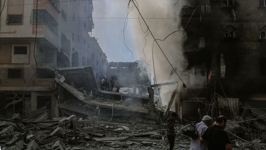 Gazans walk by ruins of buildings from Israeli airstrikes