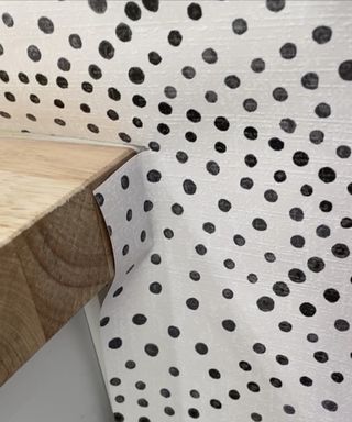 A close up shot of black and white spotted wallpaper pasted to wooden desk.jpeg