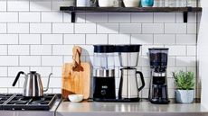 A stainless steel OXO 9-cup brewer on a kitchen counter against white subway tile wall. 