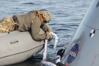 A winch cable is attached to the Orion spacecraft during recovery operations training.