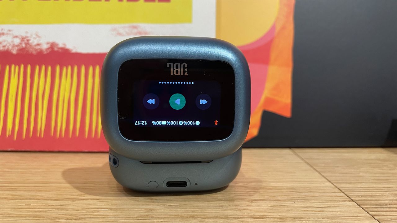 A close-up of the screen on the case for the JBL Live Beam 3 buds. It is displaying playback controls.