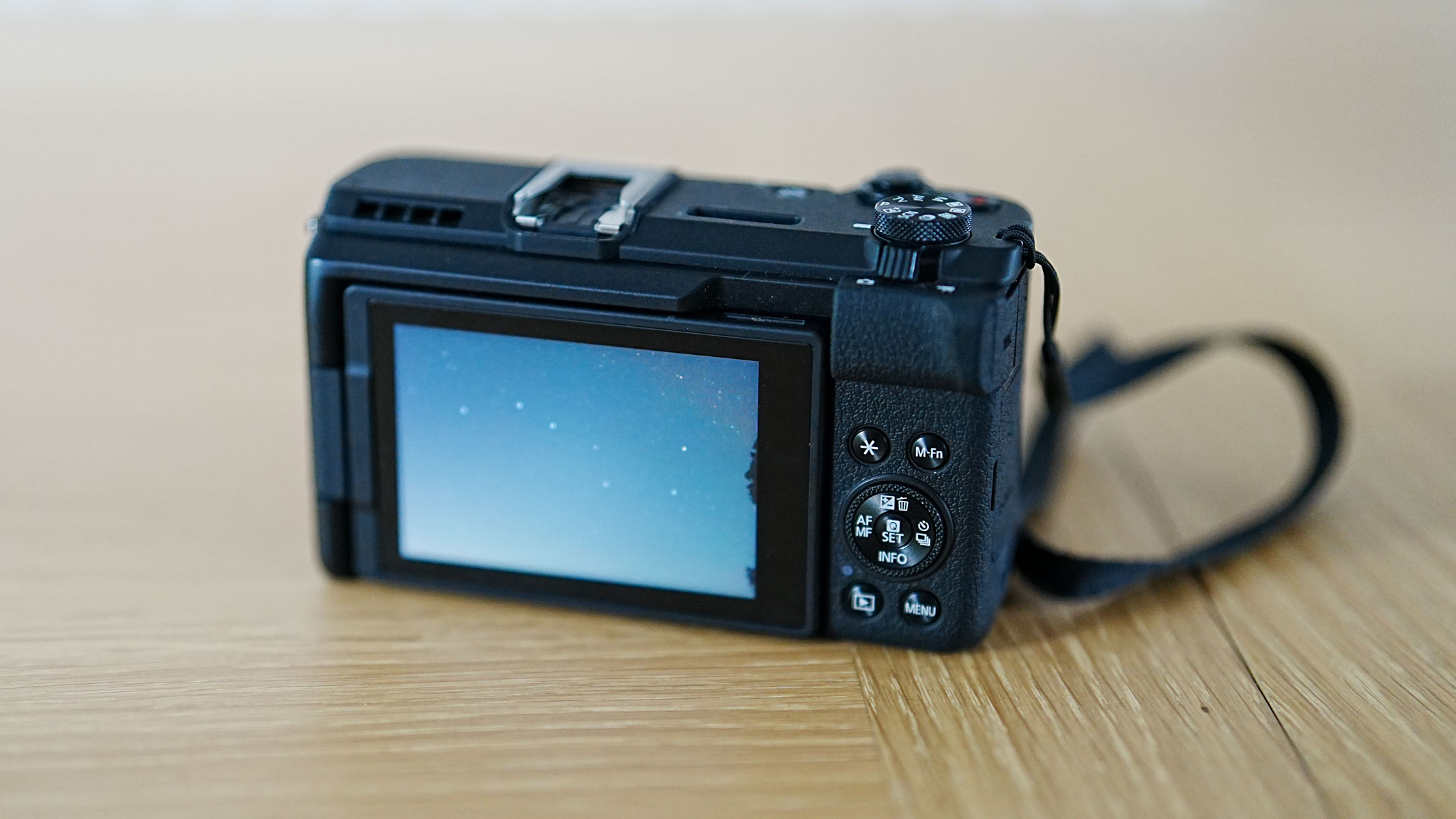 The Canon Powershot V1 on a wooden table showing an astrophoto on the screen.
