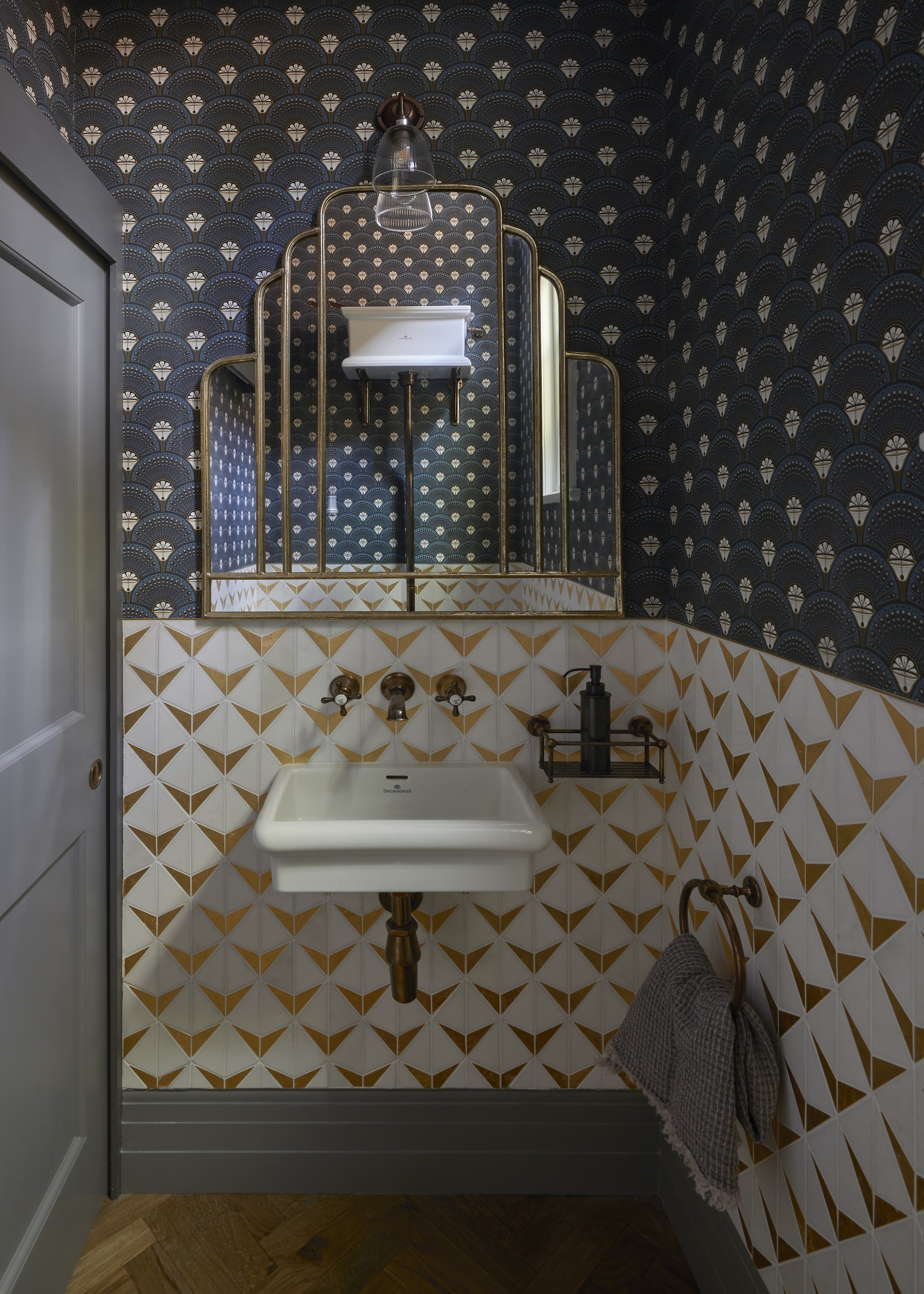 A bathroom with mixed and contrasting wallpaper as well as a small sink and mirror above it