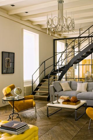 Living room with yellow and grey color scheme and statement staircase