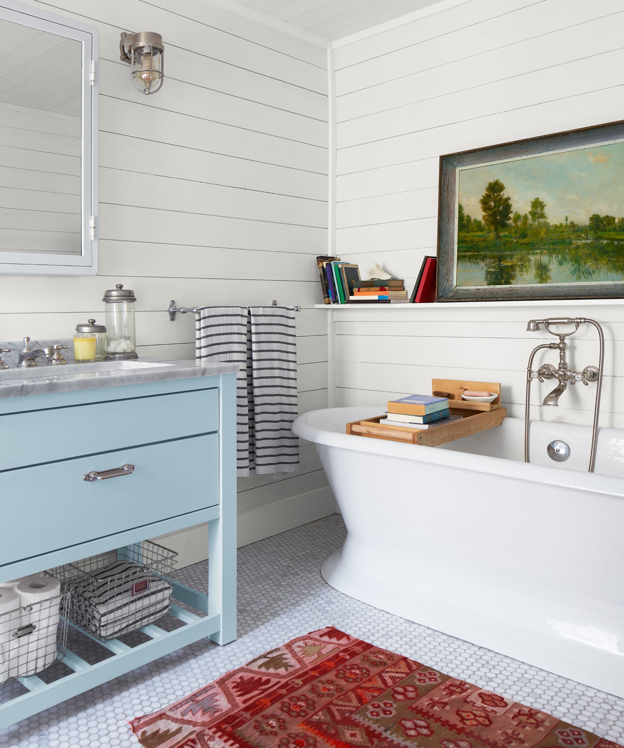 A coastal bathroom with white paneled walls and a blue bathroom vanity