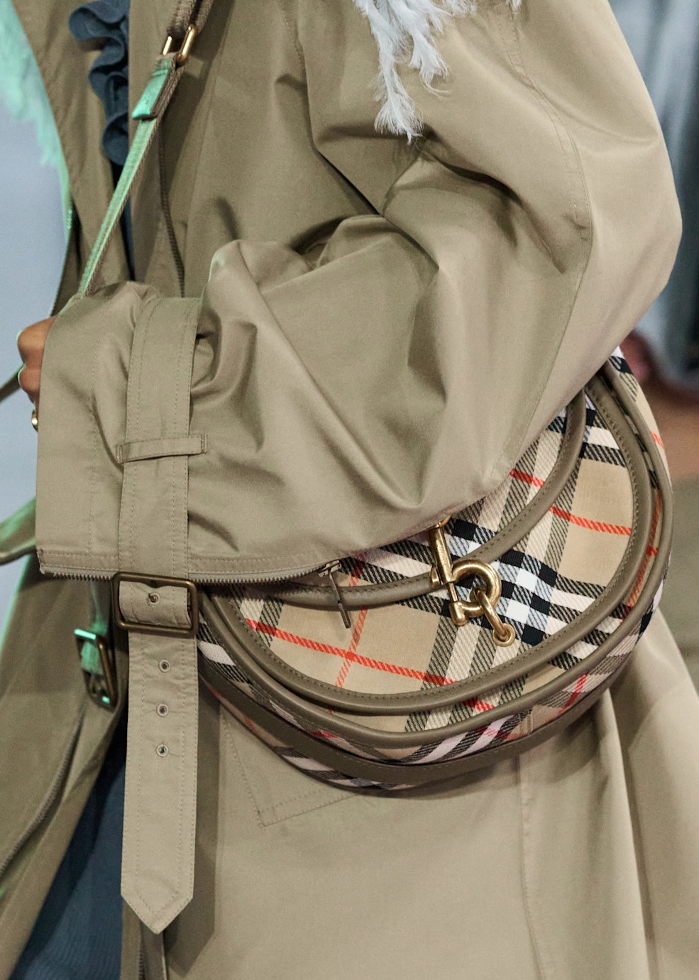 woman wearing a trench coat and carrying a plaid bag