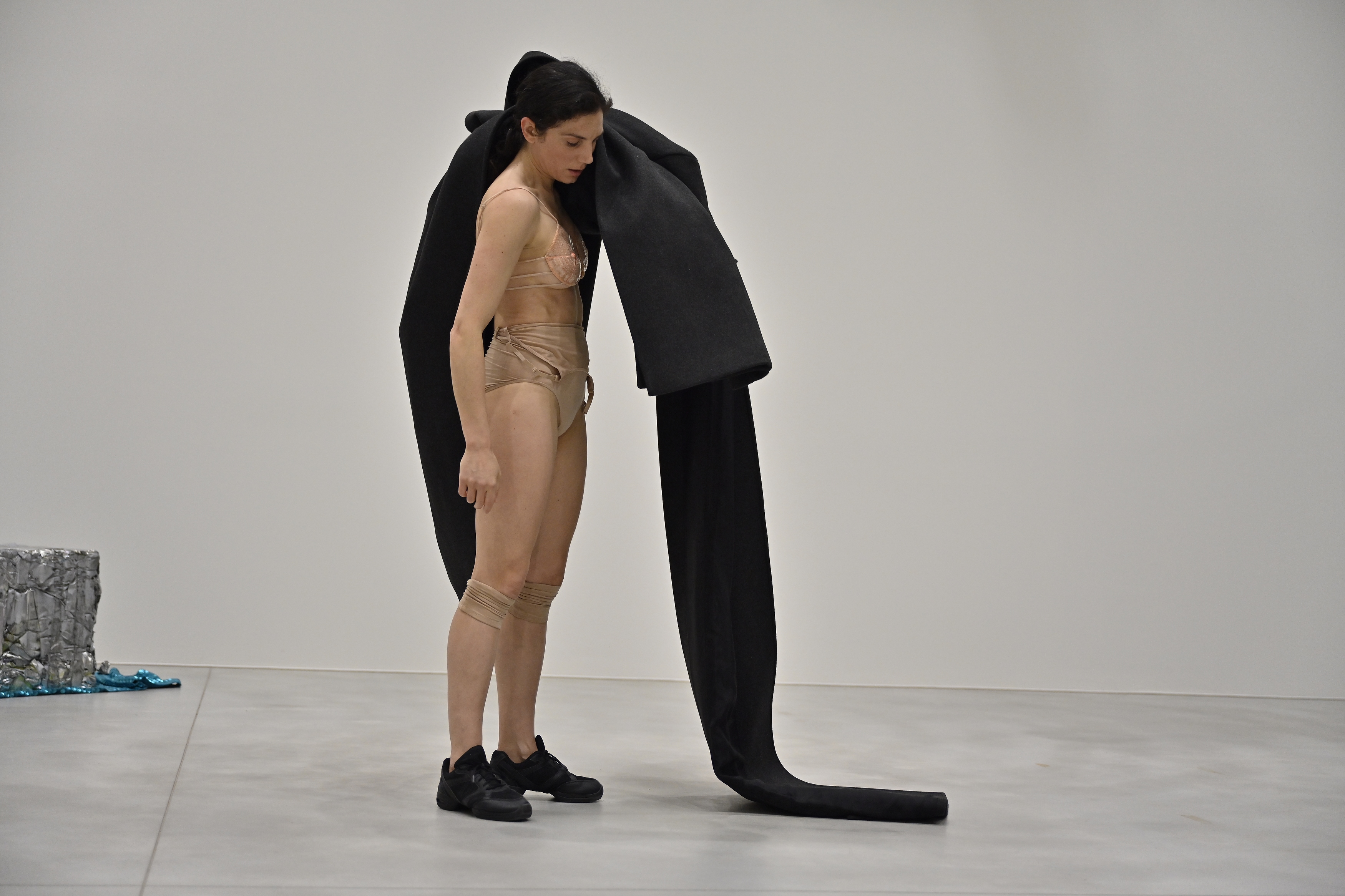 Woman dancer in underwear carries Bottega Veneta coat over shoulder