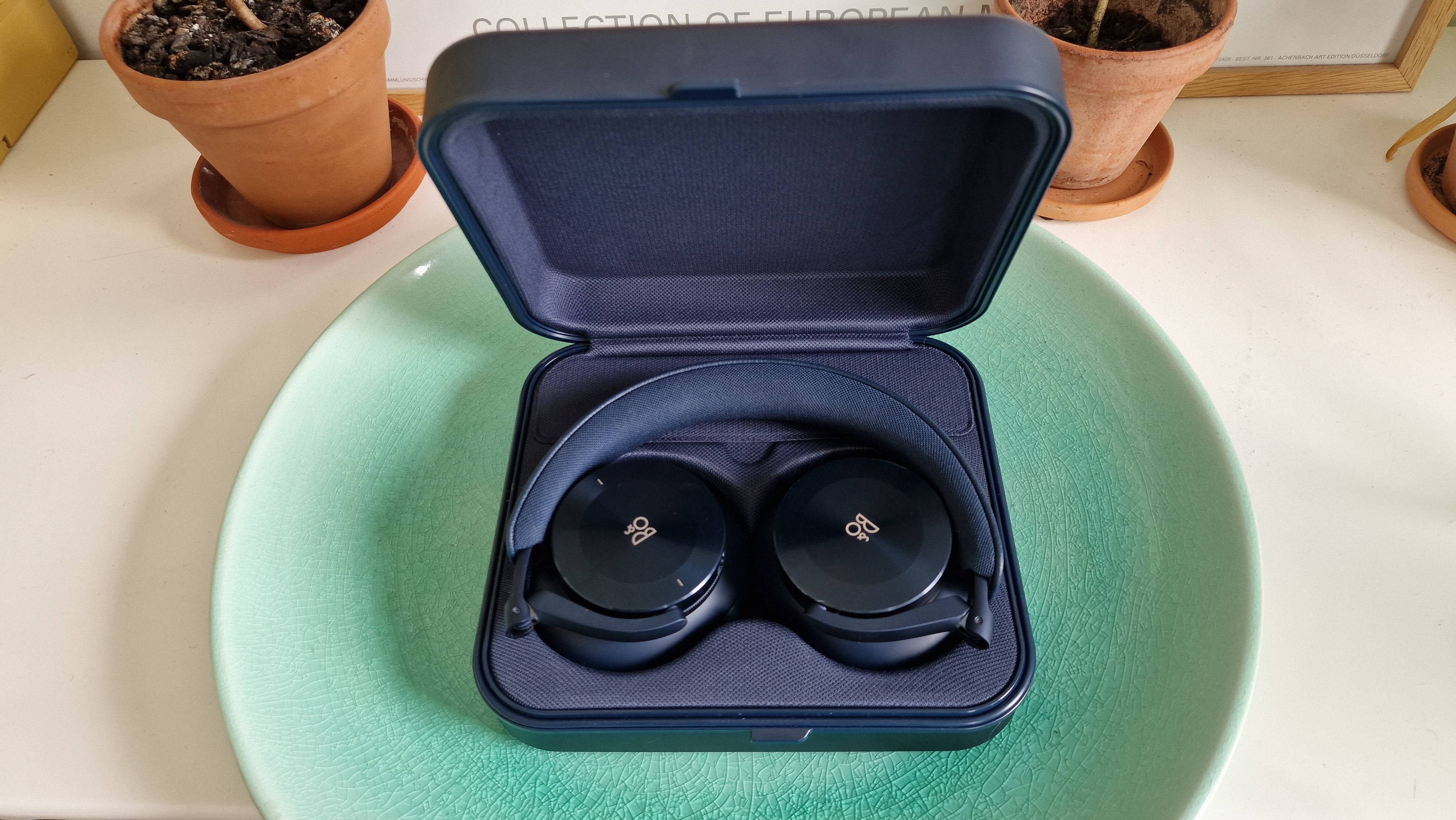 Beoplay H95 i etuiet i et grønt fad på et bord