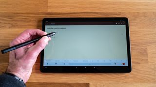 Hand writing on an Amazon Fire Max 11 tablet in a wooden surface