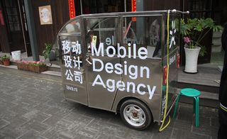 A small, silver vehicle with "Mobile Design Agency" printed on the side